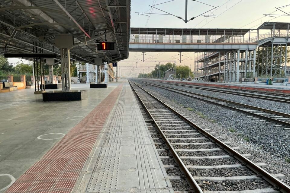 An Indian railway station platform with a train on the tracks